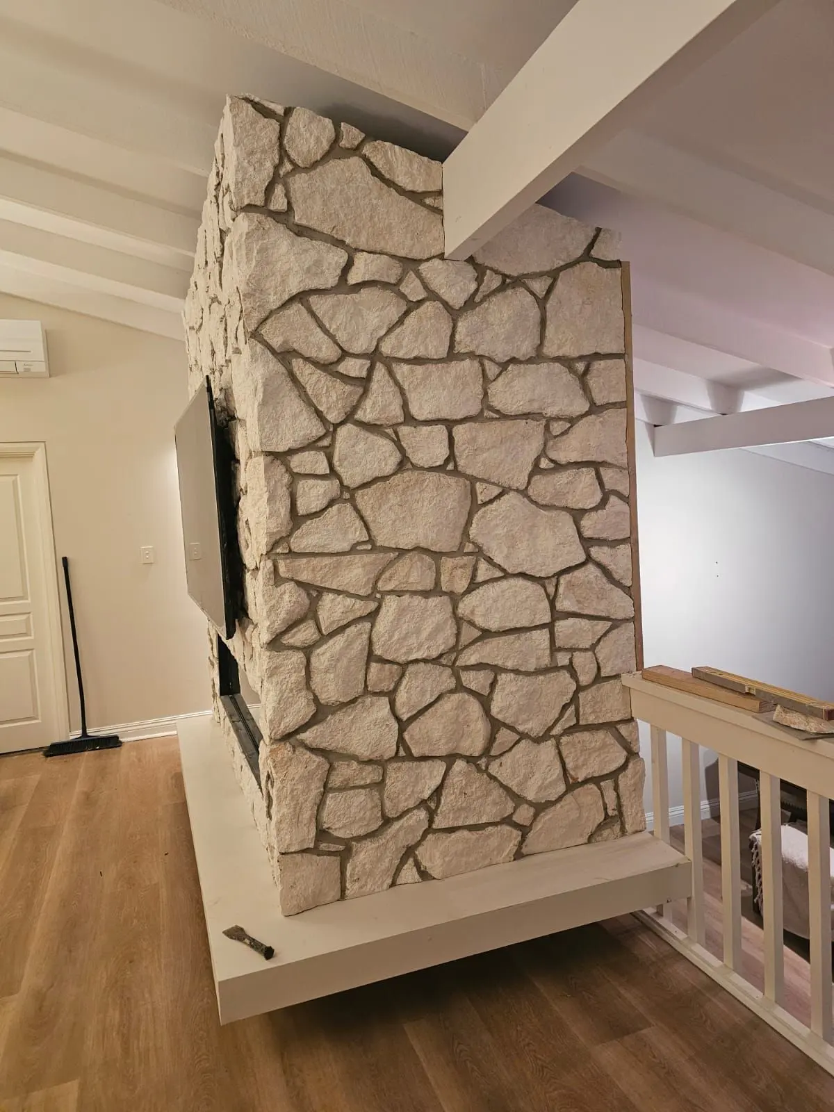Completed irregular sandstone fireplace feature wall with television and inset fire