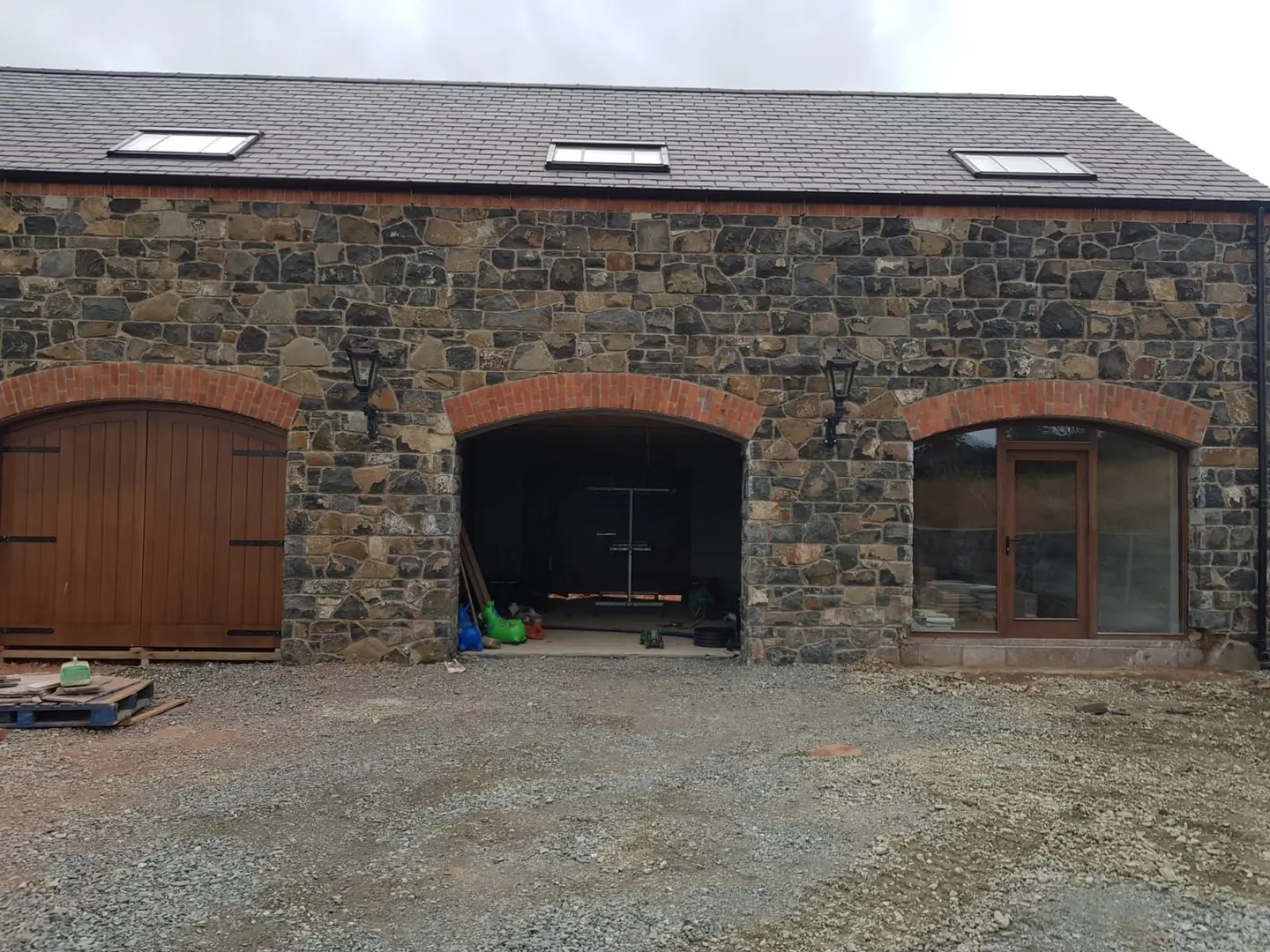 Irish house facade clad in stone with brick arches over the garage openings
