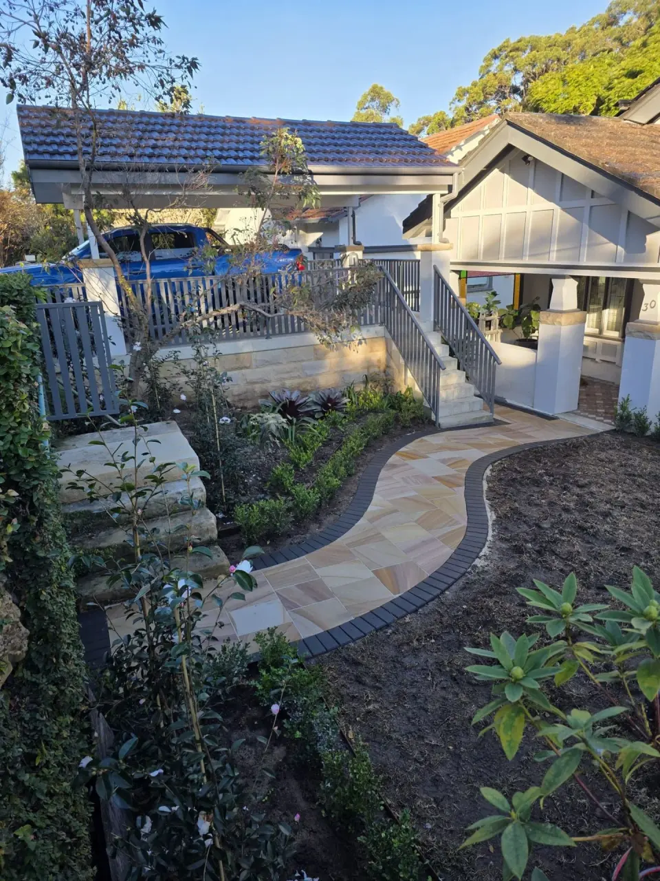 Sandstone garden path with curved brick borders